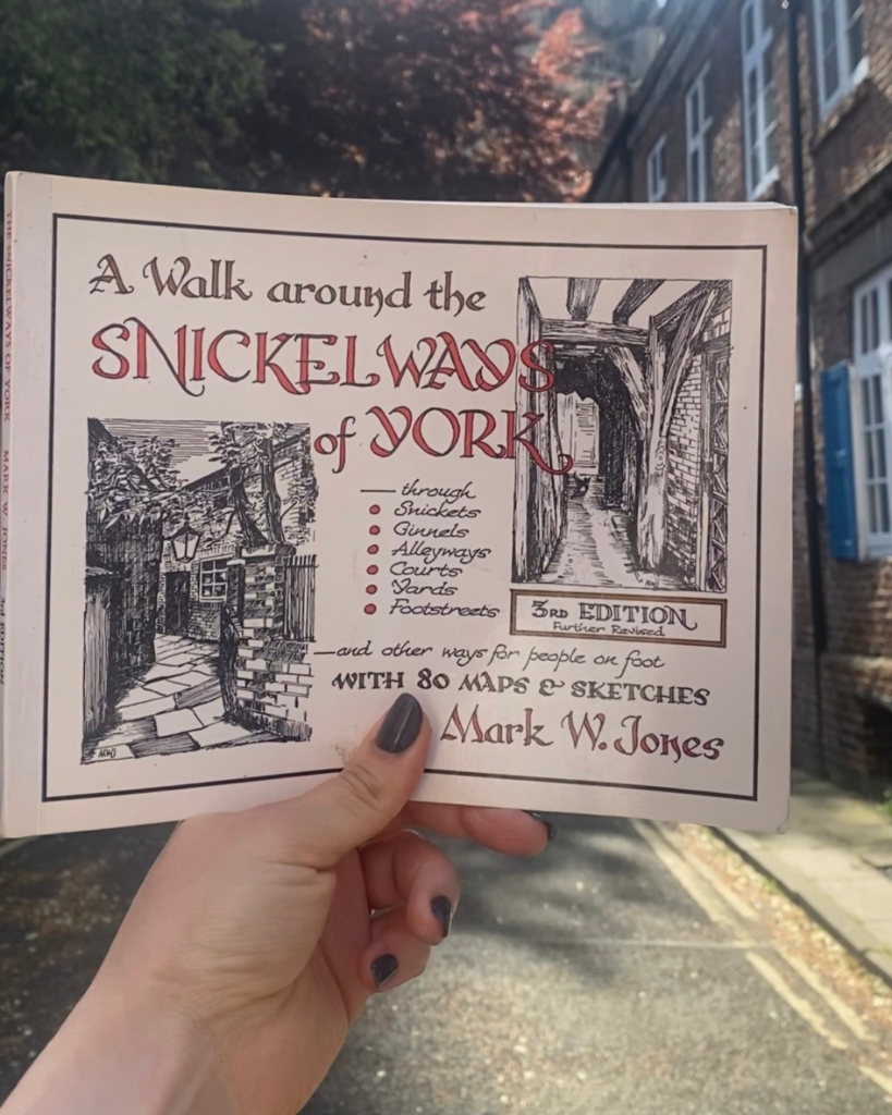A hand holds a book called "A Walk around the Snickelways of York" 