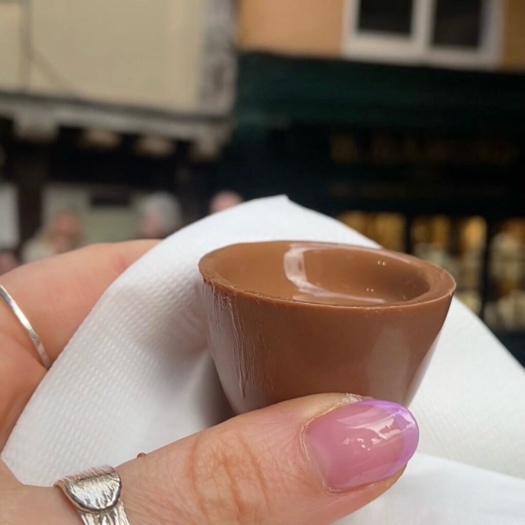 A close up of a milk chocolate cup containing melted milk chocolate. 