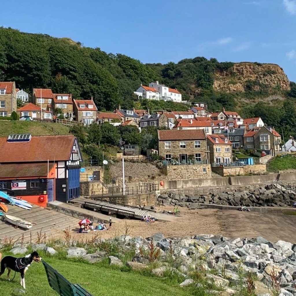 Picturesque cottages with burnt orange roofs hug the side of the cliff, with the beach below.